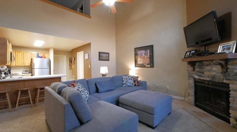 Living room featuring large wide cozy couch wood burning fireplace four barstools, and cabinet with games, puzzles, and various conveniences.