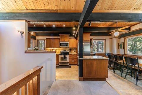 The shared living space boasts high ceilings with exposed wood beams, soaring windows, and an open layout.