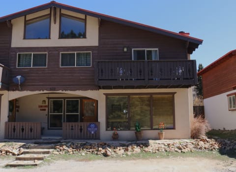 A charming alpine-style vacation rental building with warm wood siding, multiple levels, and a private balcony set in a scenic mountain neighborhood.