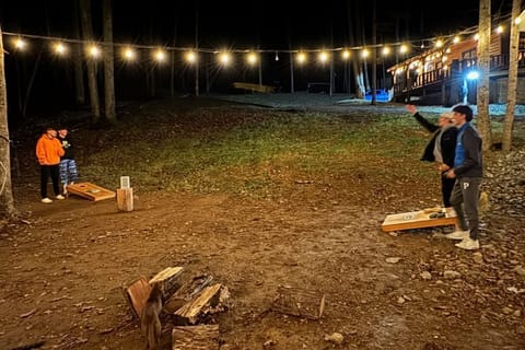 String lights illuminate the camp fire area.  Large area for a game of Cornhole.