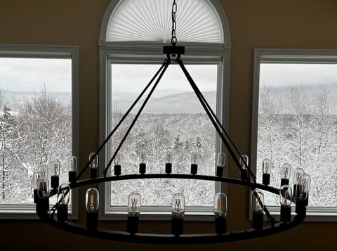 Elegant chandelier framed by stunning winter mountain views—adding warmth and charm to your Vermont retreat.