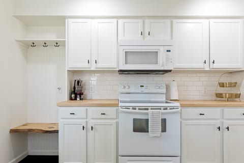 A modern kitchen with white cabinets, wooden countertops, and a cozy, inviting ambiance.