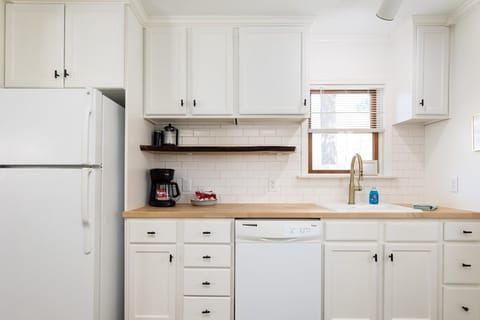 Our modern kitchen boasts white cabinets, wooden countertops, and an array of appliances, emitting a clean and organized atmosphere ideal for culinary exploration.