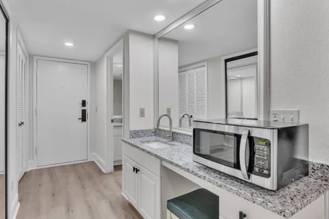 The kitchen is a pristine, all-white sanctuary. Glossy cabinetry, marble countertops, and stainless steels blend modern elegance with functionality.