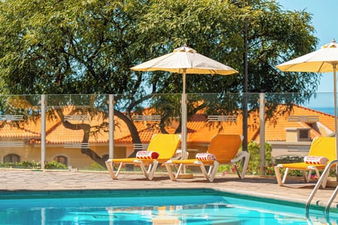 Unwind poolside on cushioned loungers beneath cooling umbrellas.