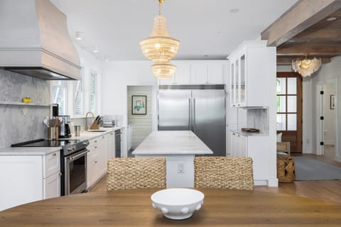 Spacious, modern kitchen featuring stainless steel appliances, quartz countertops, and designer lighting