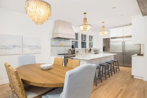 Light-filled dining space flowing into a gourmet kitchen with high-end finishes and breakfast bar seating