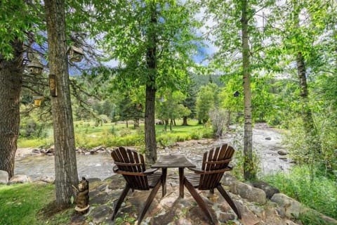 Elk River Cabin Adirondack chairs on riverbank in backyard.