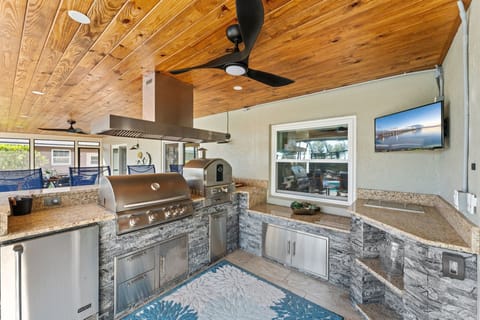 Fire up the grill in this dreamy outdoor kitchen with granite counters, a ceiling fan, and everything you need for a laid-back cookout.