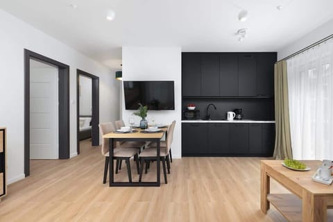 A living room combined with a dining area, featuring a gray sofa and large windows allowing plenty of natural light.
