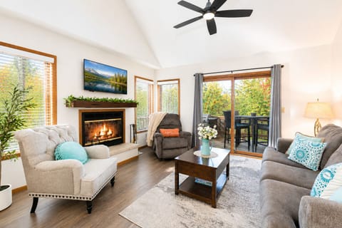 Relax by the cozy fireplace while enjoying peaceful wooded views