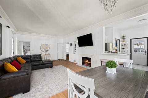 Open-concept living room with 75" TV, fireplace, leather sofas, and kitchen view.