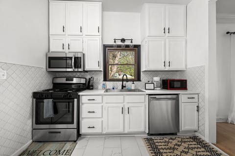 Well-equipped kitchen with white cabinetry and quartz countertops.