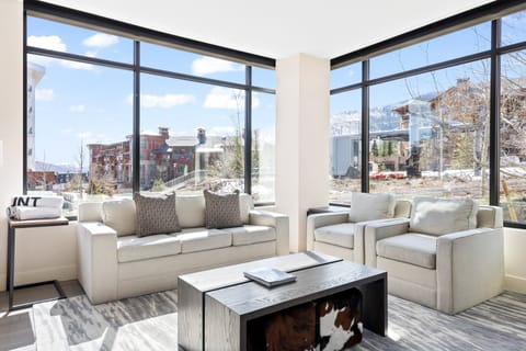 - Bright living room with floor to ceiling windows and mountain views  
- Comfortable seating to unwind after skiing or hiking adventures  
- Natural light fills this cozy condo retreat with alpine scenery