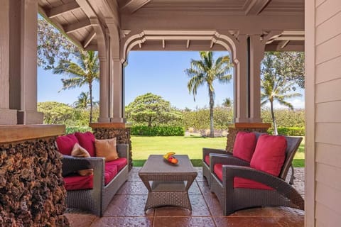 Covered lanai with plush seating and tropical landscaping