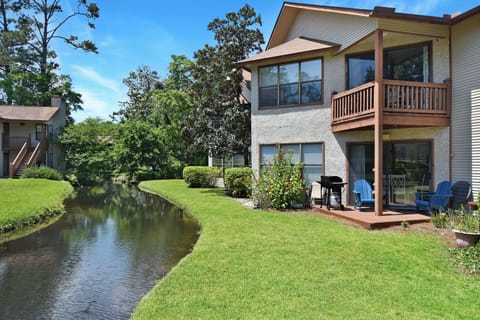 Ground-Floor Condo with Creek View - Exterior view of Harbour Oaks 409 with lawn, creek, and patio area beside the condo.