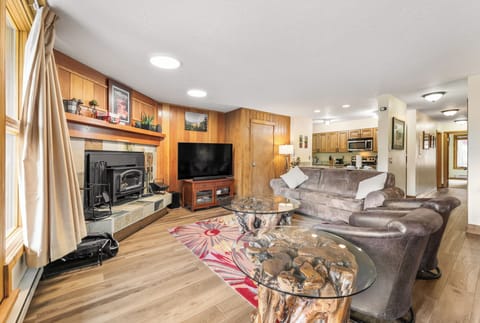 Living area with smart TV, hardwood flooring, access to the private balcony and a wood-burning fireplace.
