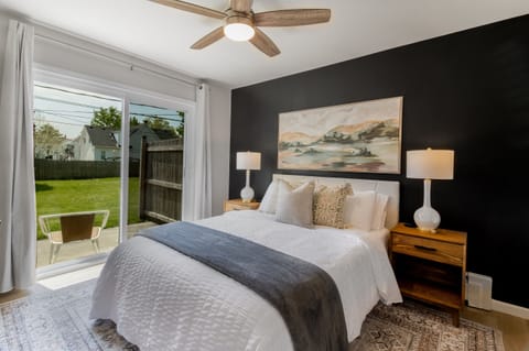 Elegant bedroom oasis featuring a dramatic black accent wall and artwork, with direct garden access for a tranquil awakening.