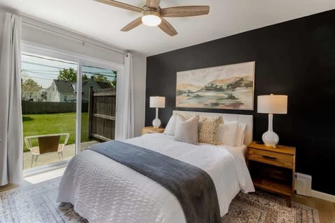 Elegant bedroom oasis featuring a dramatic black accent wall and artwork, with direct garden access for a tranquil awakening.