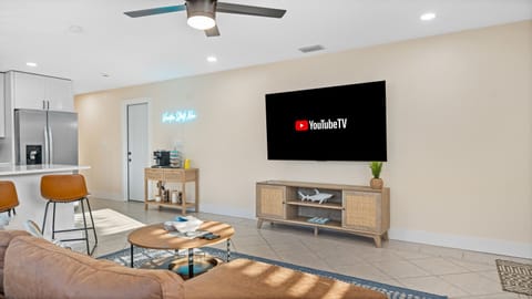 Cocoa Beach living room with a neon-lit coffee cart, wicker accents, and leather seating—perfect for breezy relaxation and laid-back seaside charm.