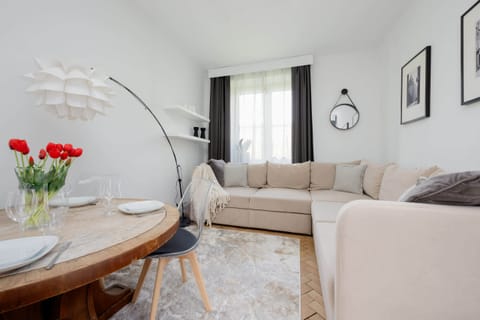 The living room is decorated in light tones with a large beige corner sofa.