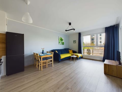 Spacious living room with dining area dedicated for four people, television with an access to cable channels, double sofa bed, and kitchenette.