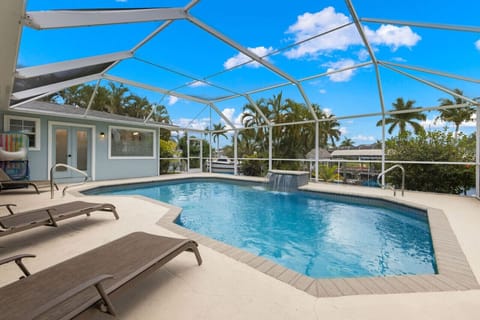 Relax in this tranquil backyard with a heated saltwater pool, waterfall, and sun loungers, all overlooking the serene canal—your perfect escape in paradise.