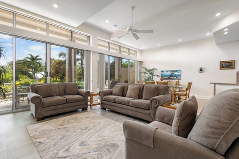 Sink into plush comfort in this airy living room, where sunlight streams through floor-to-ceiling windows revealing lush tropical views. Perfect for unwinding after your adventures.