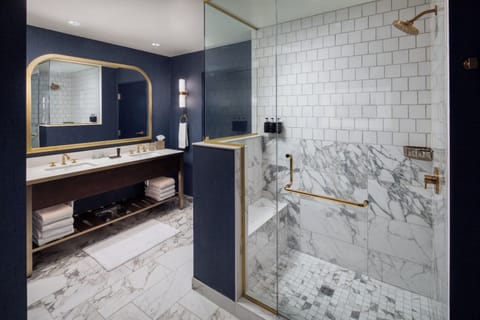 Step into a polished bathroom with marble finishes and glass shower.