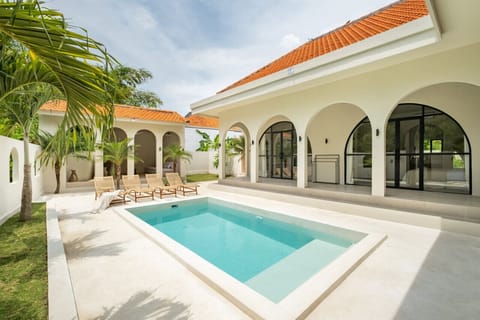 a luxurious white villa with a refreshing pool, surrounded by tropical plants, offering a serene and inviting outdoor living space.