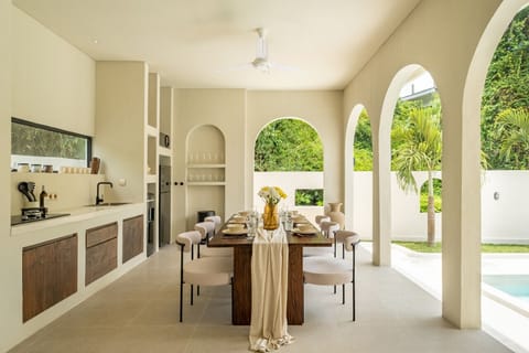 A beautifully designed kitchen-dining space, accented with natural wood and fresh flowers, offers a perfect blend of style and serenity.