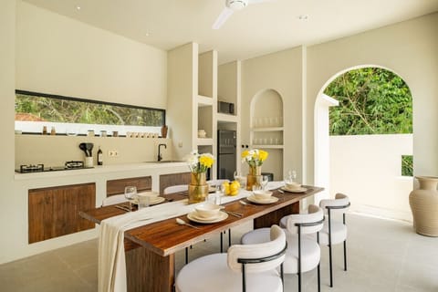 A beautifully designed kitchen-dining space, accented with natural wood and fresh flowers, offers a perfect blend of style and serenity.