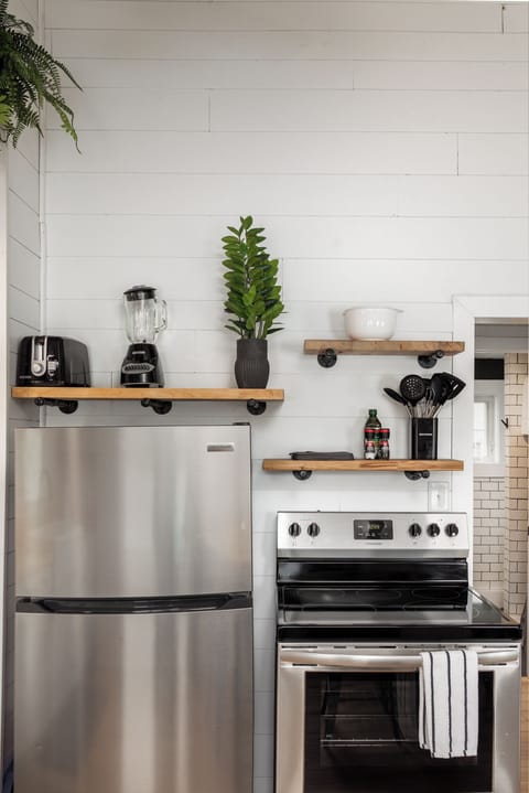 In the contemporary kitchen, a stainless steel fridge stands alongside shelves adorned with dishes and a coffee maker, while a window offers a serene view of the tranquil lake.