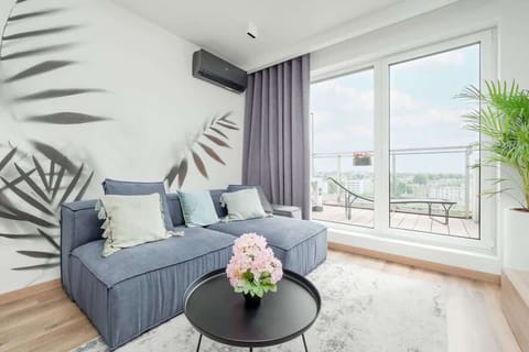 The living room with a large window, light walls, and gray furniture creates a space full of light and modern elegance.