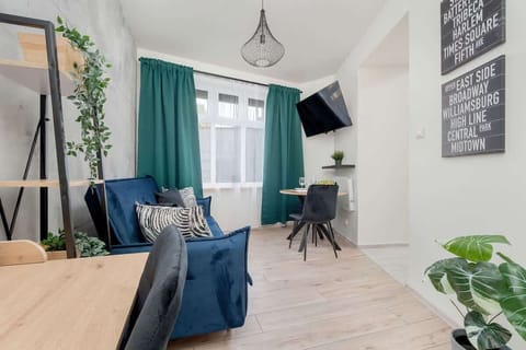 A bright living room with a navy-blue sofa, white walls, and large windows bringing in natural light.

