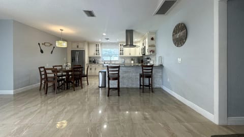 Open-concept dining and kitchen area with 6 seating dining table & 2 bar stools.