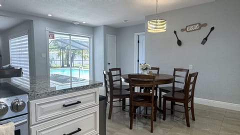 Open-concept dining and kitchen area with 6 seating dining table & 2 bar stools.