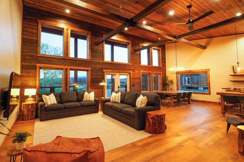 View from the cabin's main entry of the great room with exposed beams, wood accents, circle sawn wood floors, and abundant south-facing windows for great light throughout the year.