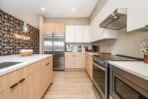 Fully equipped modern kitchen featuring culinary essentials, stainless steel appliances, and island bar seating.