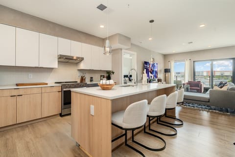 Fully equipped modern kitchen featuring culinary essentials, stainless steel appliances, and island bar seating.