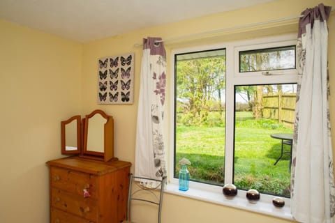 Bedroom with chest of drawers with mirrors. Butterfly wall art. Ornaments on windowsill