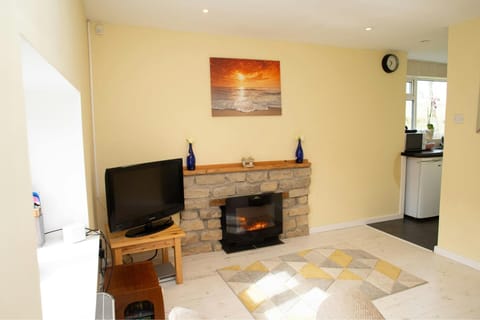 Living room with Smart TV on wooden table. Fireplace and mantle