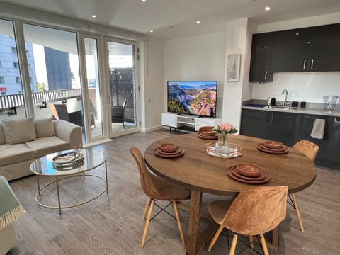 Living room with 65 inch smart TV, dining table & 4 chairs, private balcony