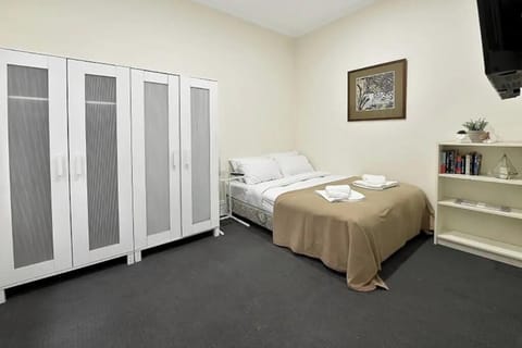 Bedroom with queen bed, wardrobes and smart tv.