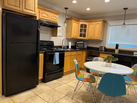 Stylish granite kitchen includes dishes, cookware, microwave, coffeemaker, dishwasher soap, baking pans, etc.