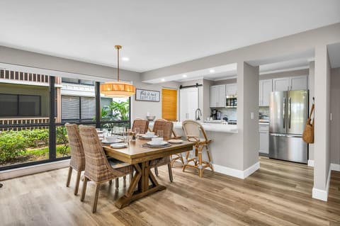 Luxury wooden dining table with 6 rattan dining chairs, and 2 additional counter stools at the kitchen counter.