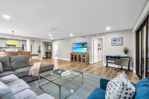 Modern living: Open concept living & dining area with large windows for ample natural light, and views for the golf course. The living room features a full-sized sleeper sofa, personal desk, and smart streaming TV with cable.