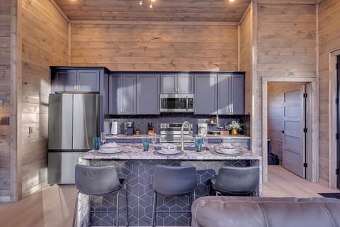Modern cabin kitchen with navy cabinetry,  and marble countertops