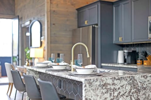Modern kitchen with marble island, elegant place settings, and gold fixtures.