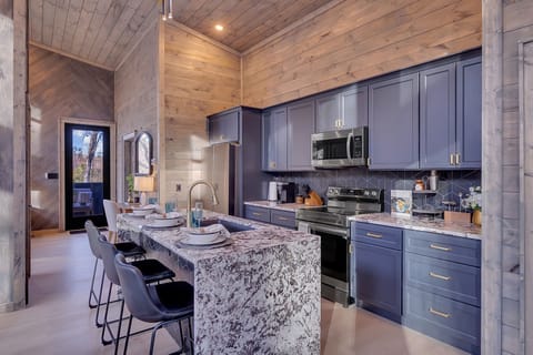 Modern cabin kitchen with navy cabinetry,  and marble countertops